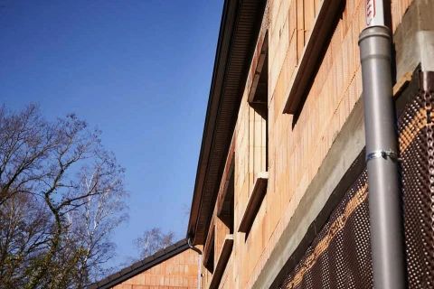 Chantier de construction extérieur avec mur en briques orange et béton en cours de finition