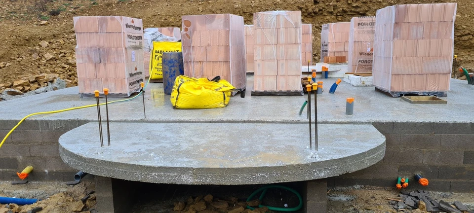 Chantier de construction extérieur avec ouvrier en équipement de sécurité consultant plans architecturaux et tablette numérique