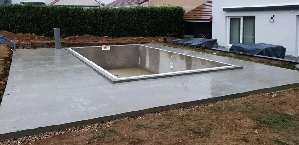 Un homme et une femme en maillots de bain se détendent au bord d'une piscine, assis sur une terrasse en bois