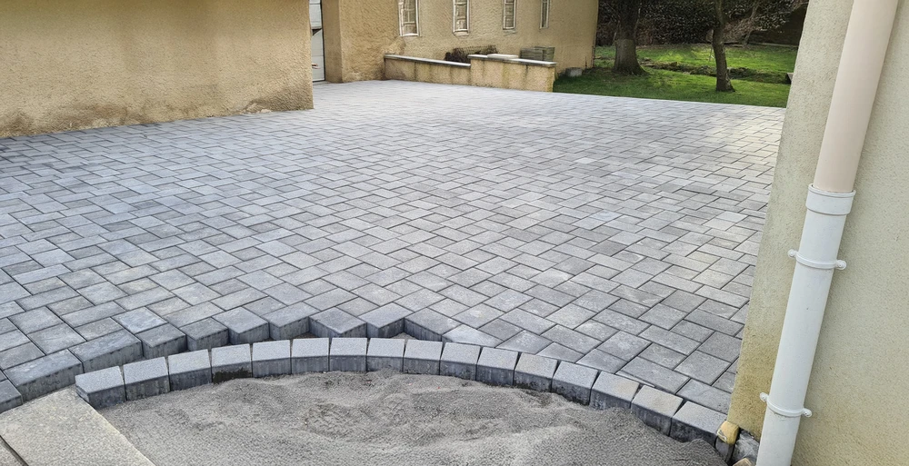 Scène extérieure résidentielle avec maison contemporaine grise à toiture tuiles et garage ouvert