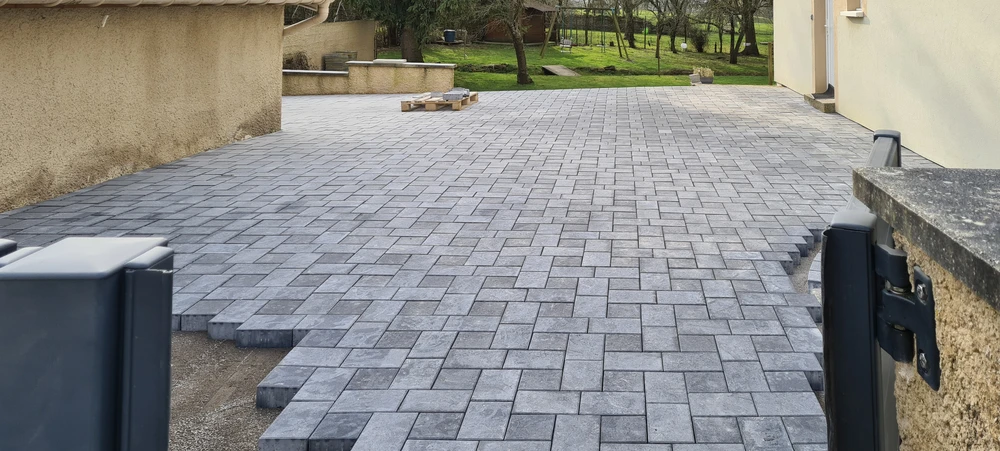 Scène extérieure résidentielle avec maison contemporaine grise à toiture tuiles et garage ouvert