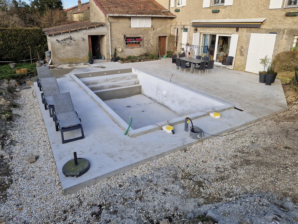 Un travailleur peint sur un pont de piscine en bois extérieur, vue de dessus